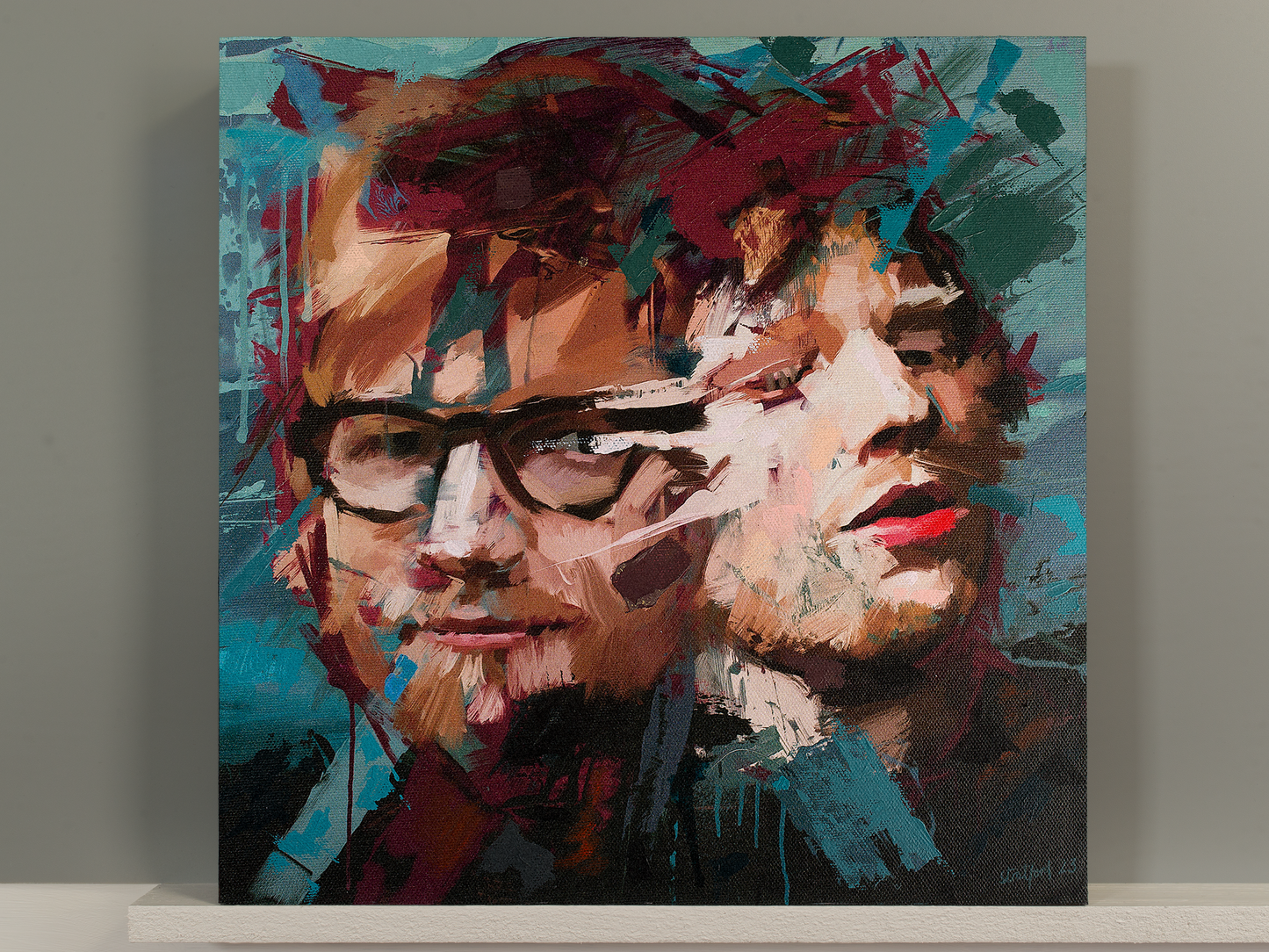 A square canvas painting of Ed Sheeran a double portrait in an abstract, expressive brushstroke style, leaning against a gray wall on a white shelf.