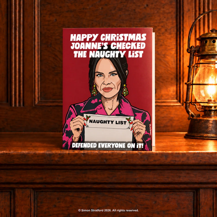 Joanne McNally Christmas card holding a naughty list: Joanne’s checked the naughty list. Defended everyone on it. Standing slightly open on a wooden mantelpiece beside a glowing antique lamp.