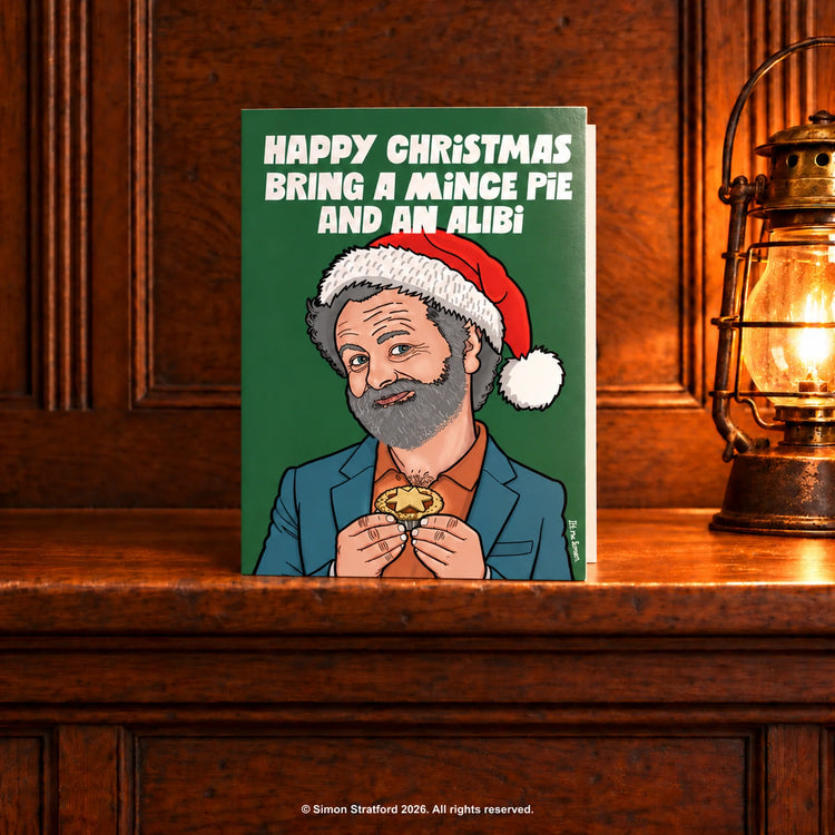Michael Sheen in a Santa hat holding a mince pie: Happy Christmas. Bring a mince pie and an alibi. Standing slightly open on a wooden mantelpiece beside a glowing antique lamp.