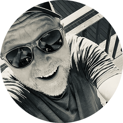 Black-and-white portrait of designer Simon Stratford wearing sunglasses